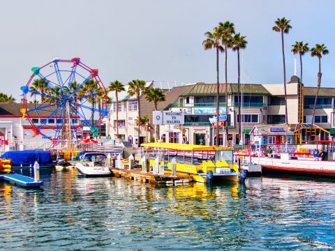 Popular pier at Balboa peninsula in Southern California with ferris wheel, tourist shops, restaurants and boats doting the harbor ferry terminal.; Courtesy of Ronnie Chua/Shutterstock