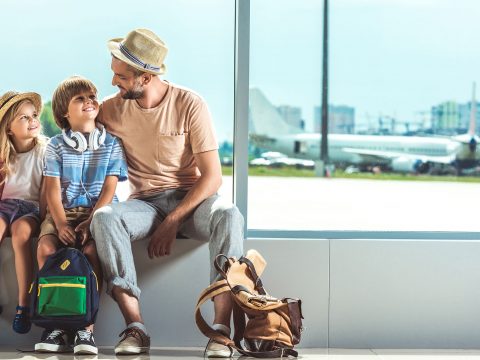 Father and Kids With Carry-On Bags at Airport; Courtesy of LightField Studios/Shutterstock.com