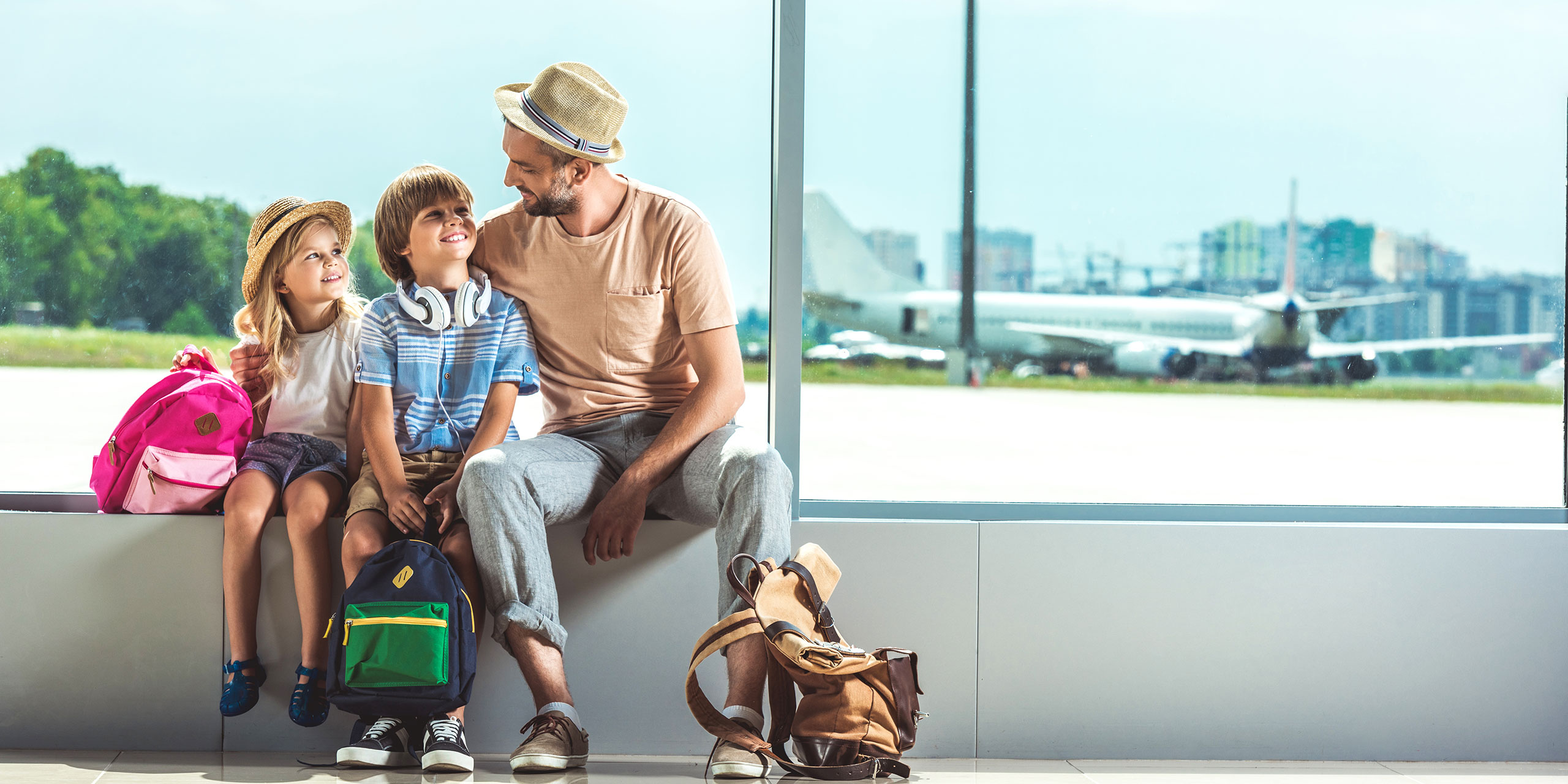 Father and Kids With Carry-On Bags at Airport; Courtesy of LightField Studios/Shutterstock.com