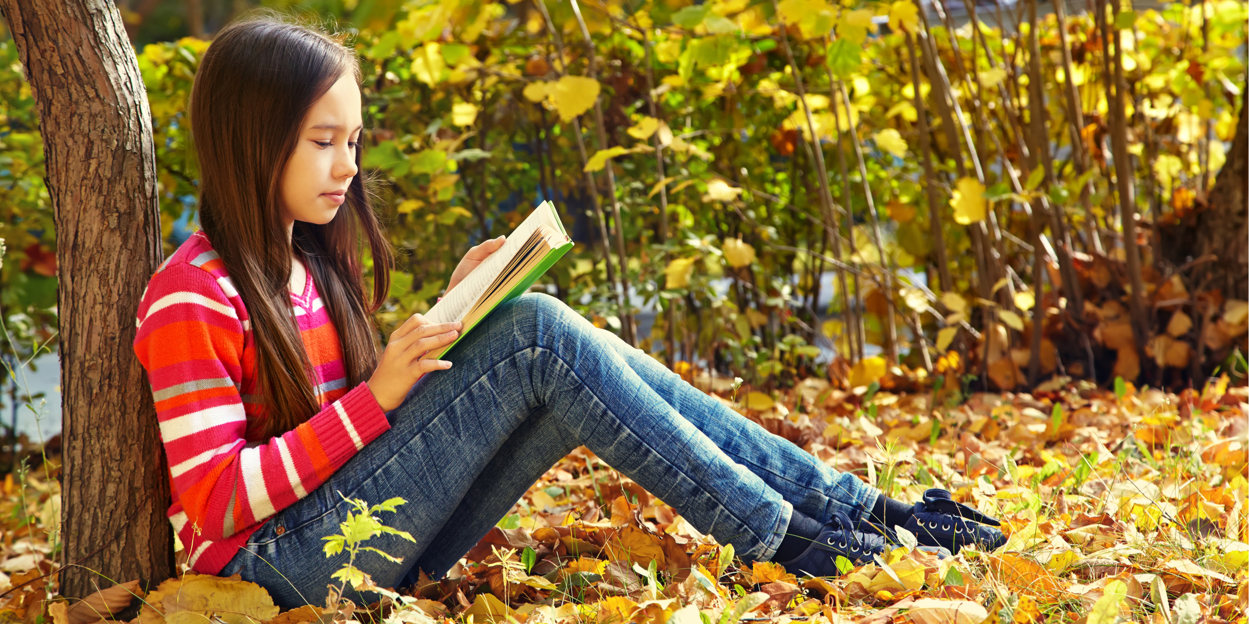 Girl reading outdoors in park.