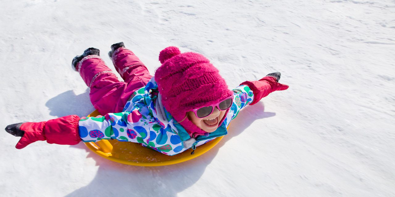 Girl Sledding in winter; Courtesy of YanLev/Shutterstock.com