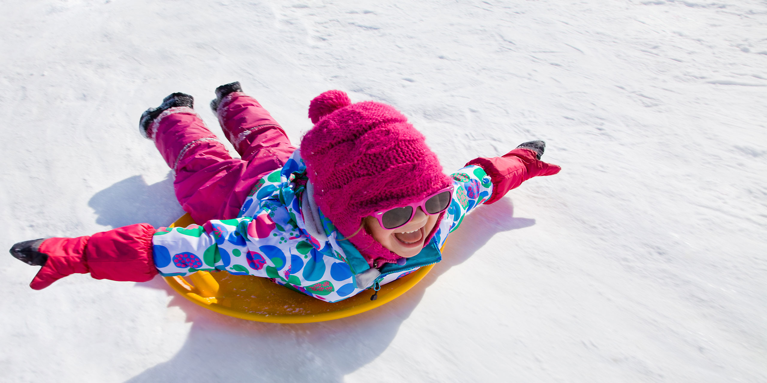 Girl Sledding in winter; Courtesy of YanLev/Shutterstock.com