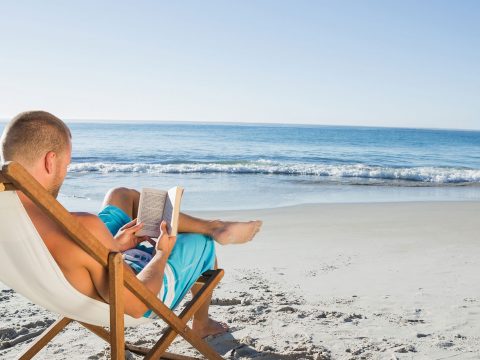Man Reading a Book on the Beach; Courtesy of wavebreakmedia/Shutterstock.com