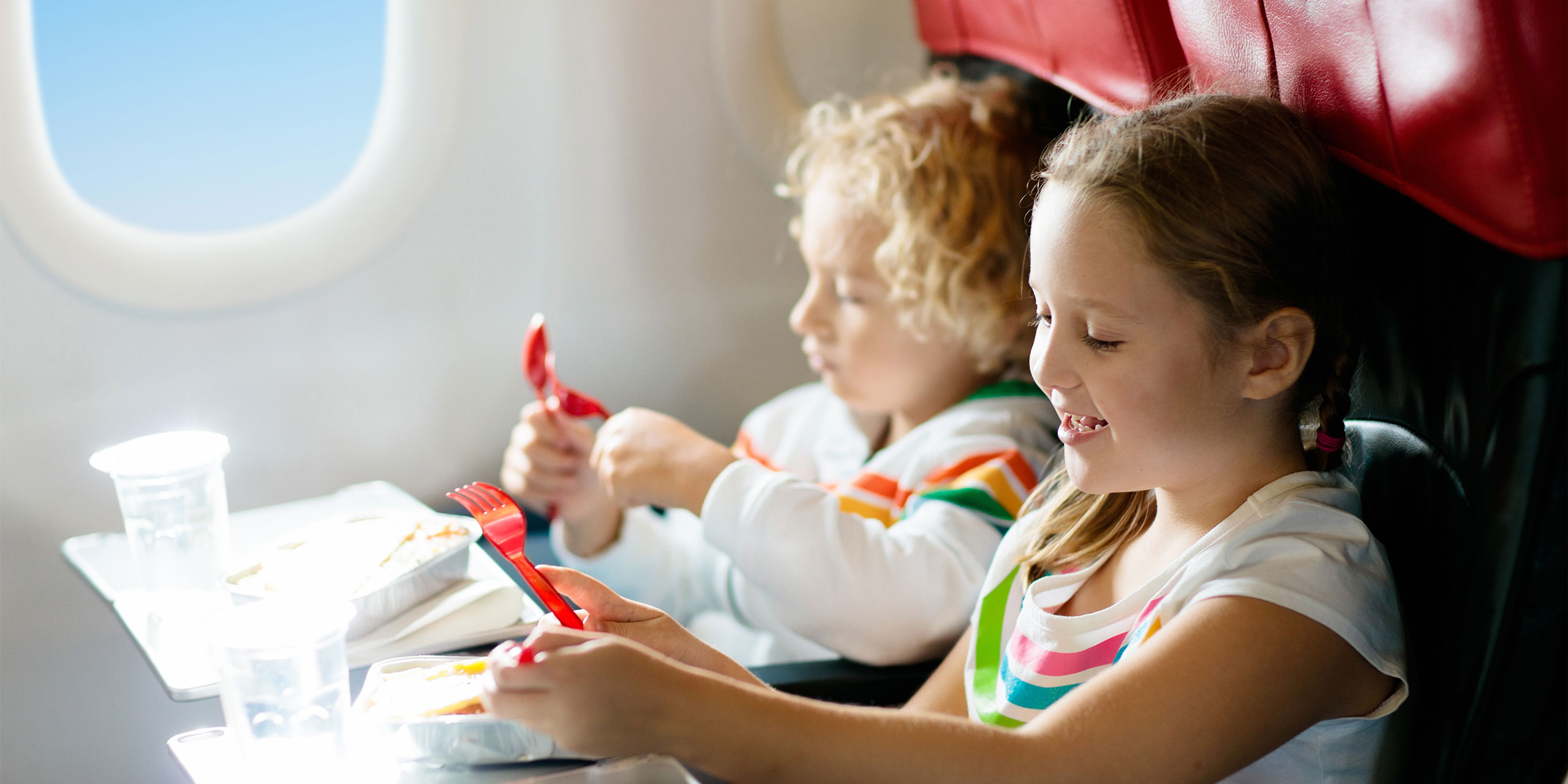Kids Eating Snacks On A Plane; Courtesy of FamVeld/Shutterstock.com