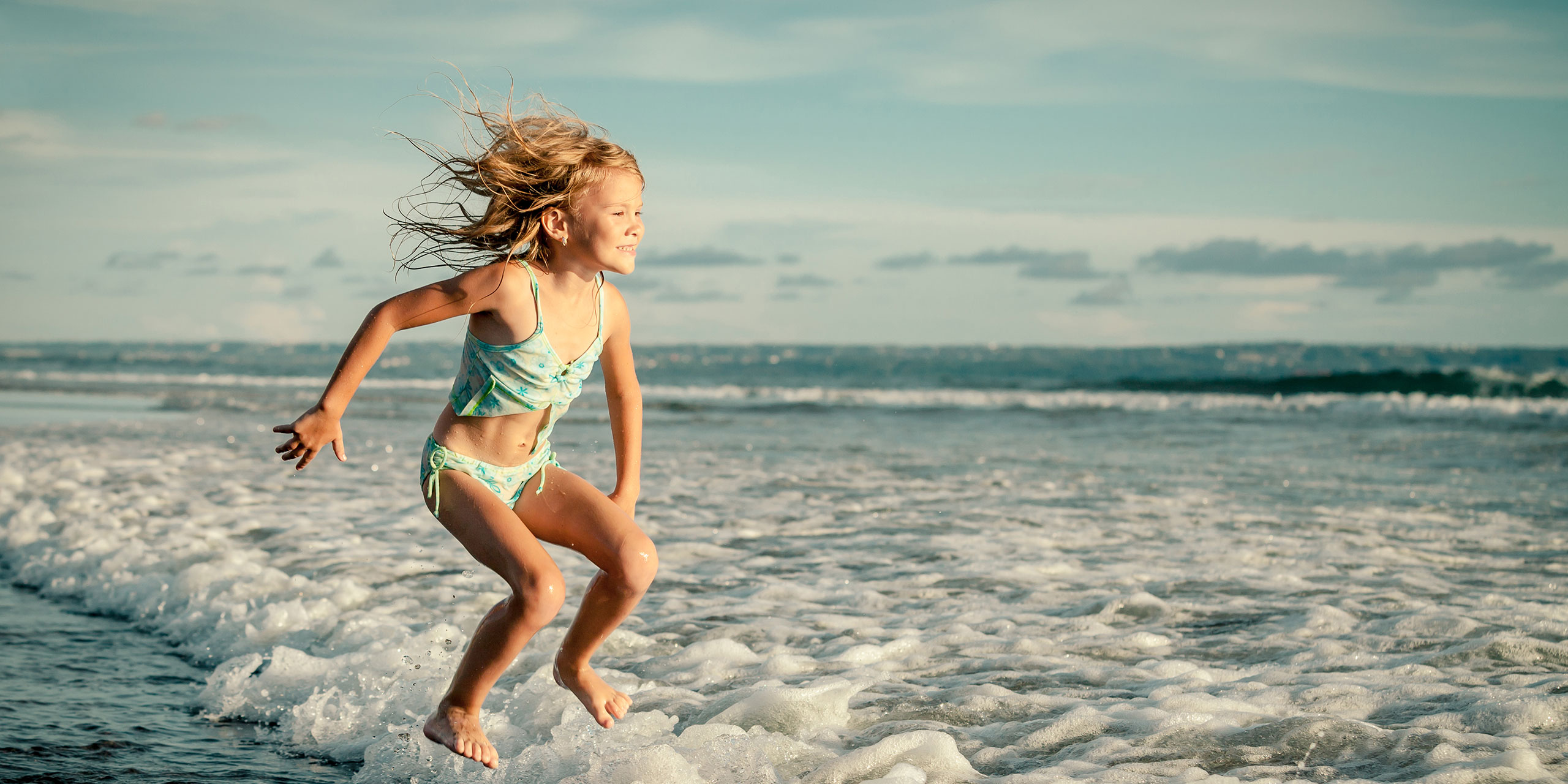 Little Girl Jumping in Ocean; Courtesy of altanaka/Shutterstock.com
