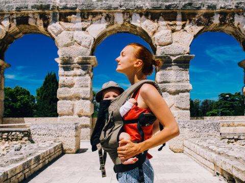 mother with baby child in carrier in the old town of Pula, Croatia; Courtesy of Natalia Deriabina/Shutterstock