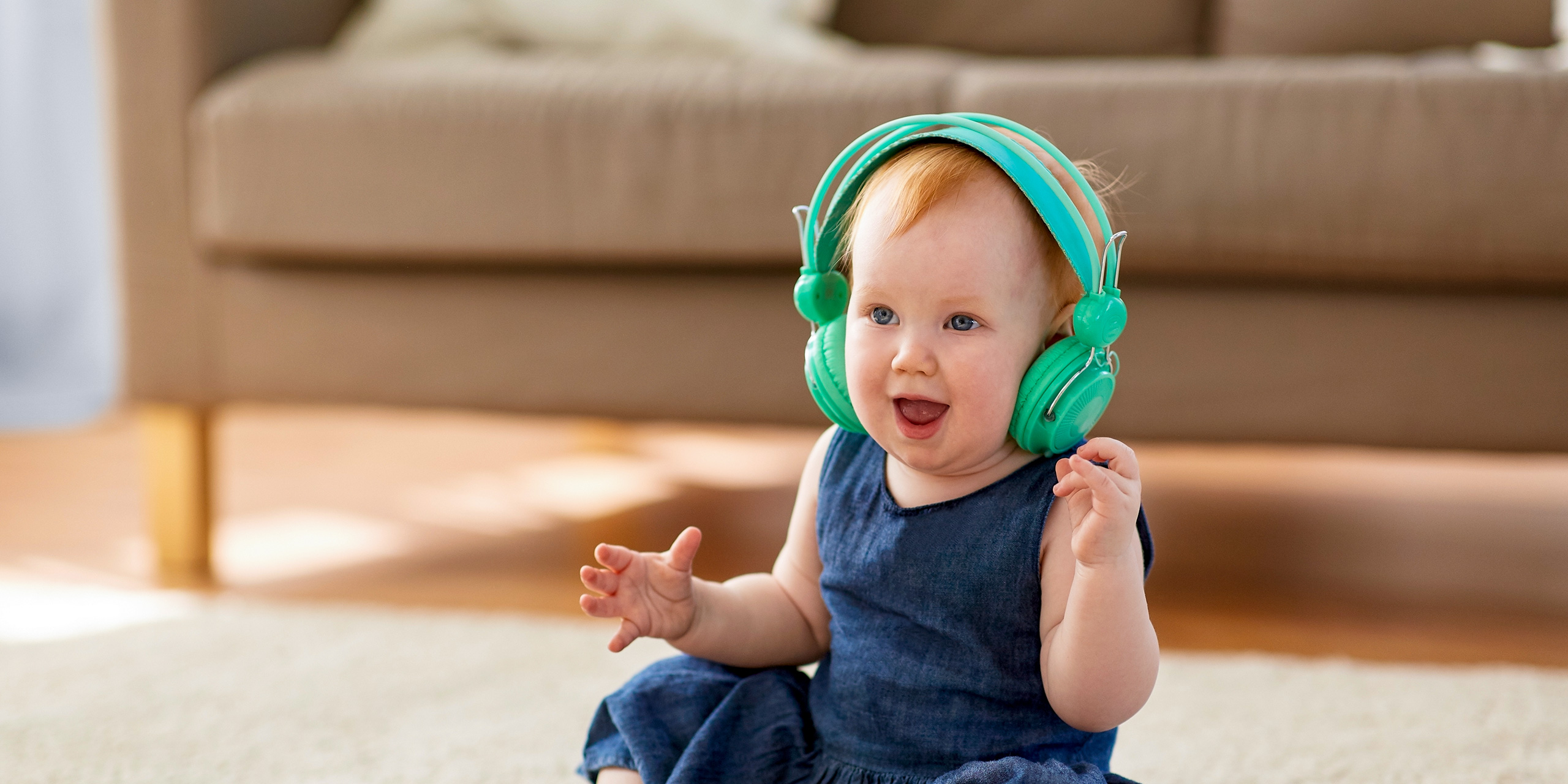 lovely redhead baby girl in headphones listening to music at home; Courtesy of Syda Productions/Shutterstock