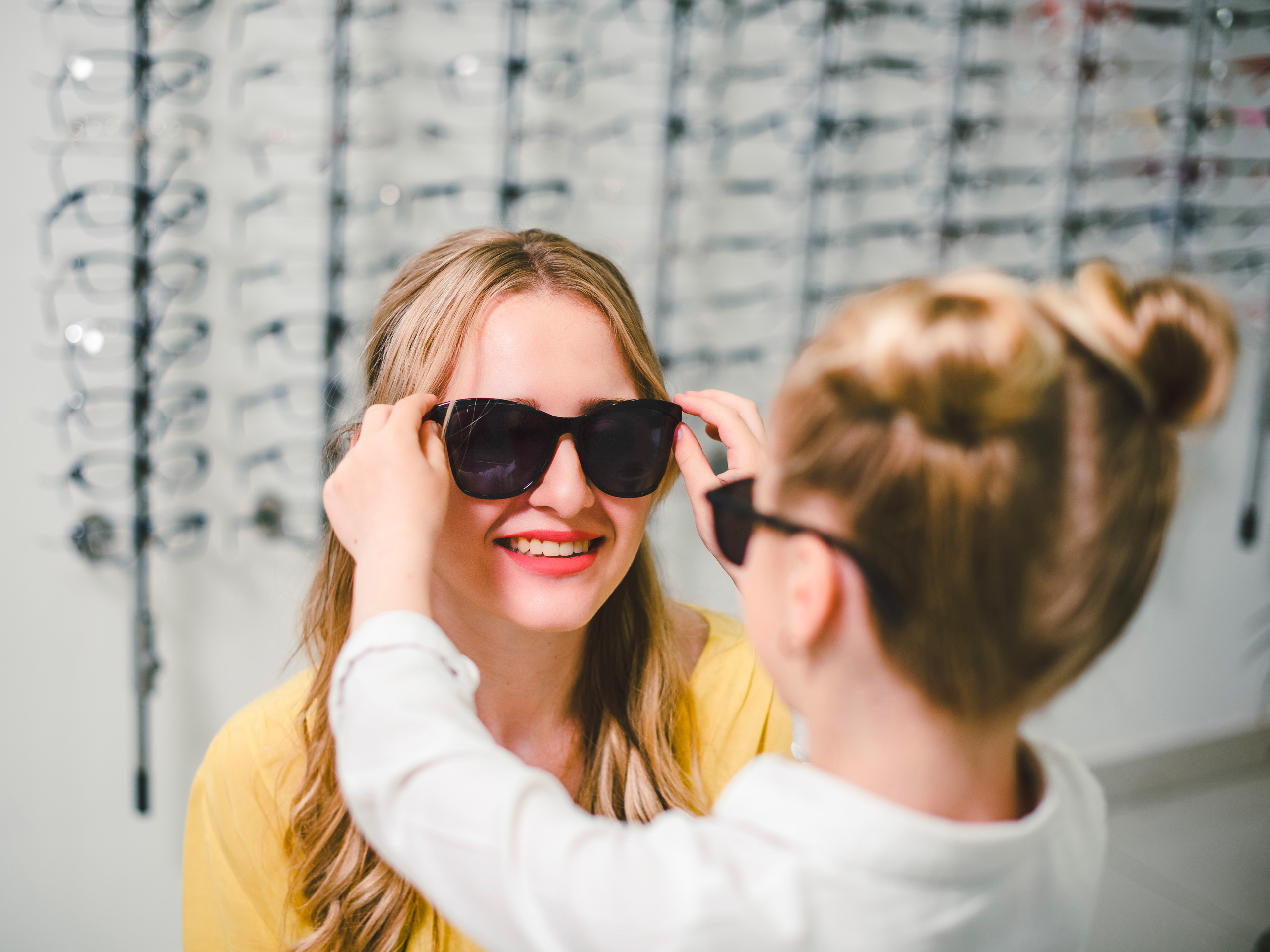 Blonde mom and daughter try the sunglasses in the boutique; Courtesy of Koshevskyi/Shutterstock