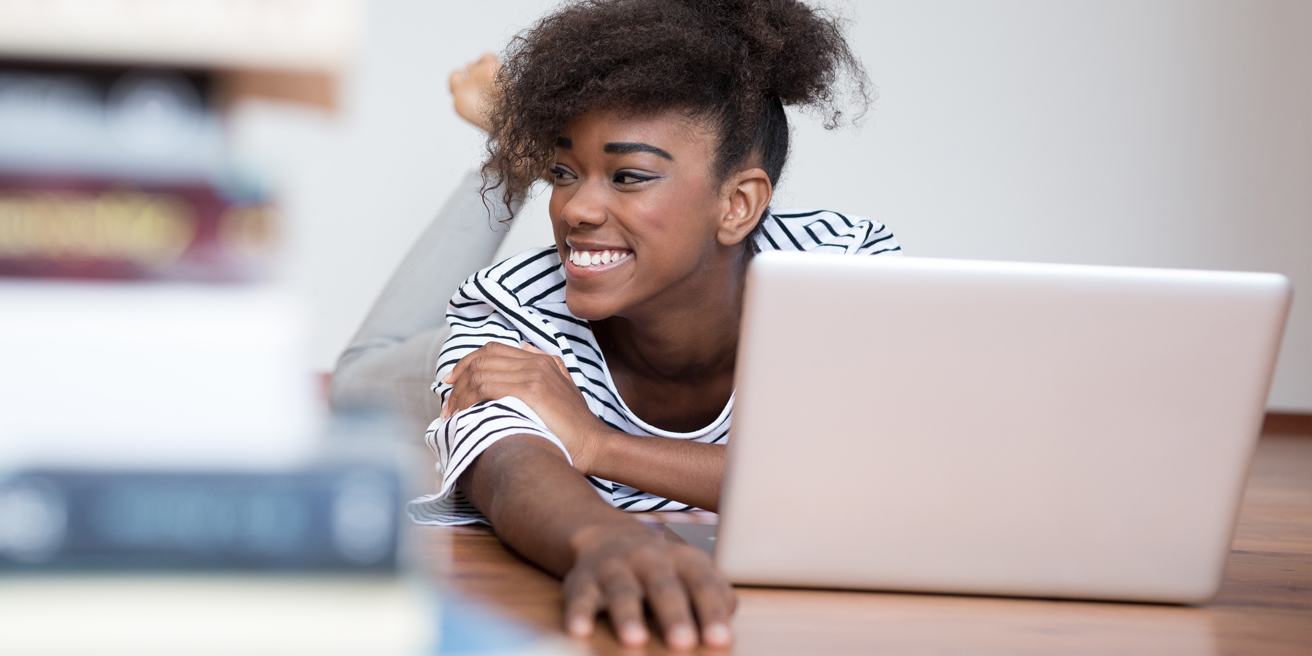 African American woman using a laptop in her living room; Courtesy of myvisuals/Shutterstock