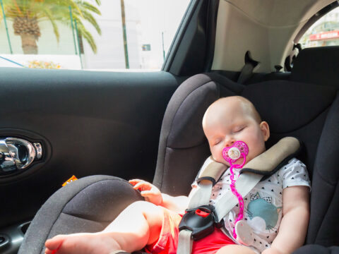 Cute baby girl is sleeping in the car on child safety seat; Courtesy of Patryk Kosmider/Shutterstock