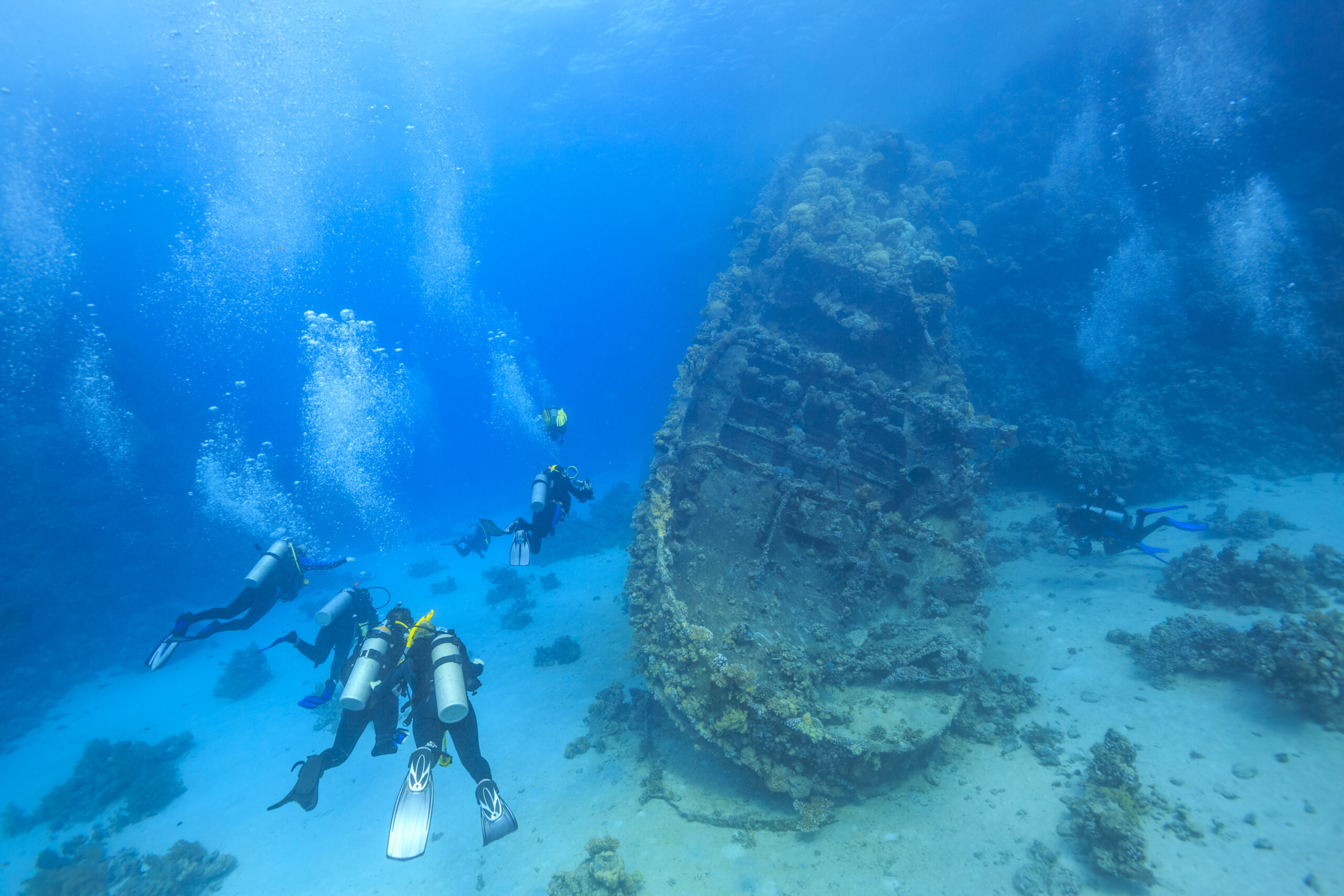 divers underwater nearing a shipwreck; Courtesy of Stas Moroz/Shutterstock