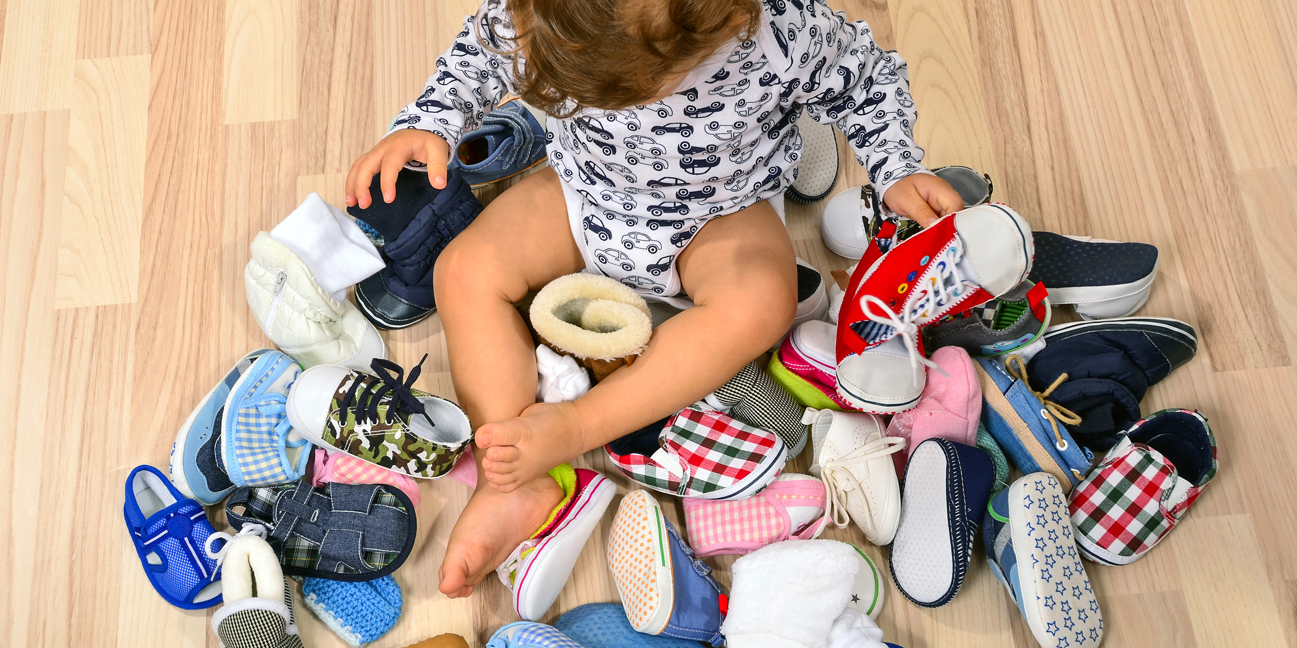 Toddler playing with a lot of baby shoes. ; Courtesy of Iulian Valentin/Shutterstock
