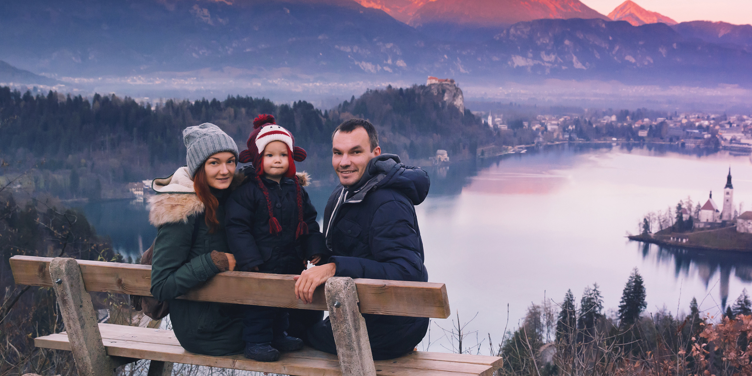 family posing for photo on lake bled in slovenia wearing weinter gear; Courtesy of Natalia Deriabina/Shutterstock