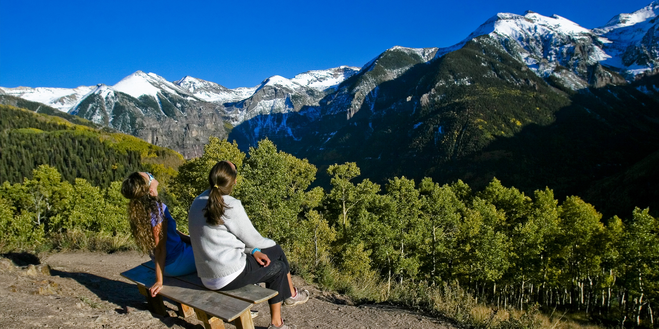 family mom and daughter sit on top of mountain and look at view; Courtesy Colorado Tourism Office