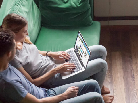parents research travel on their laptop sitting on sofa; Courtesy of fizkes/Shutterstock
