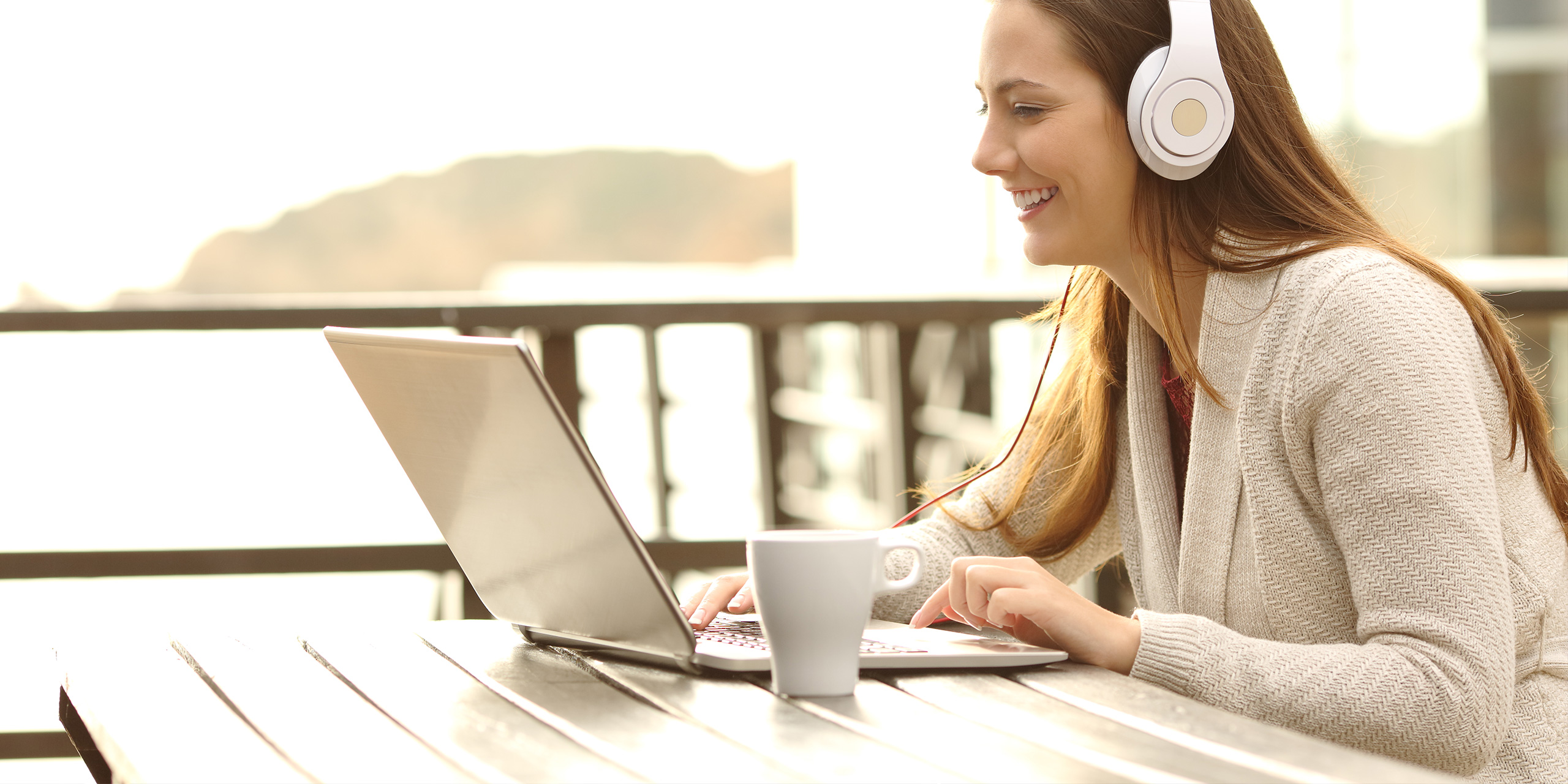 teenager using laptop and headphones on vacation; Courtesy of Antonio Guillem/Shutterstock