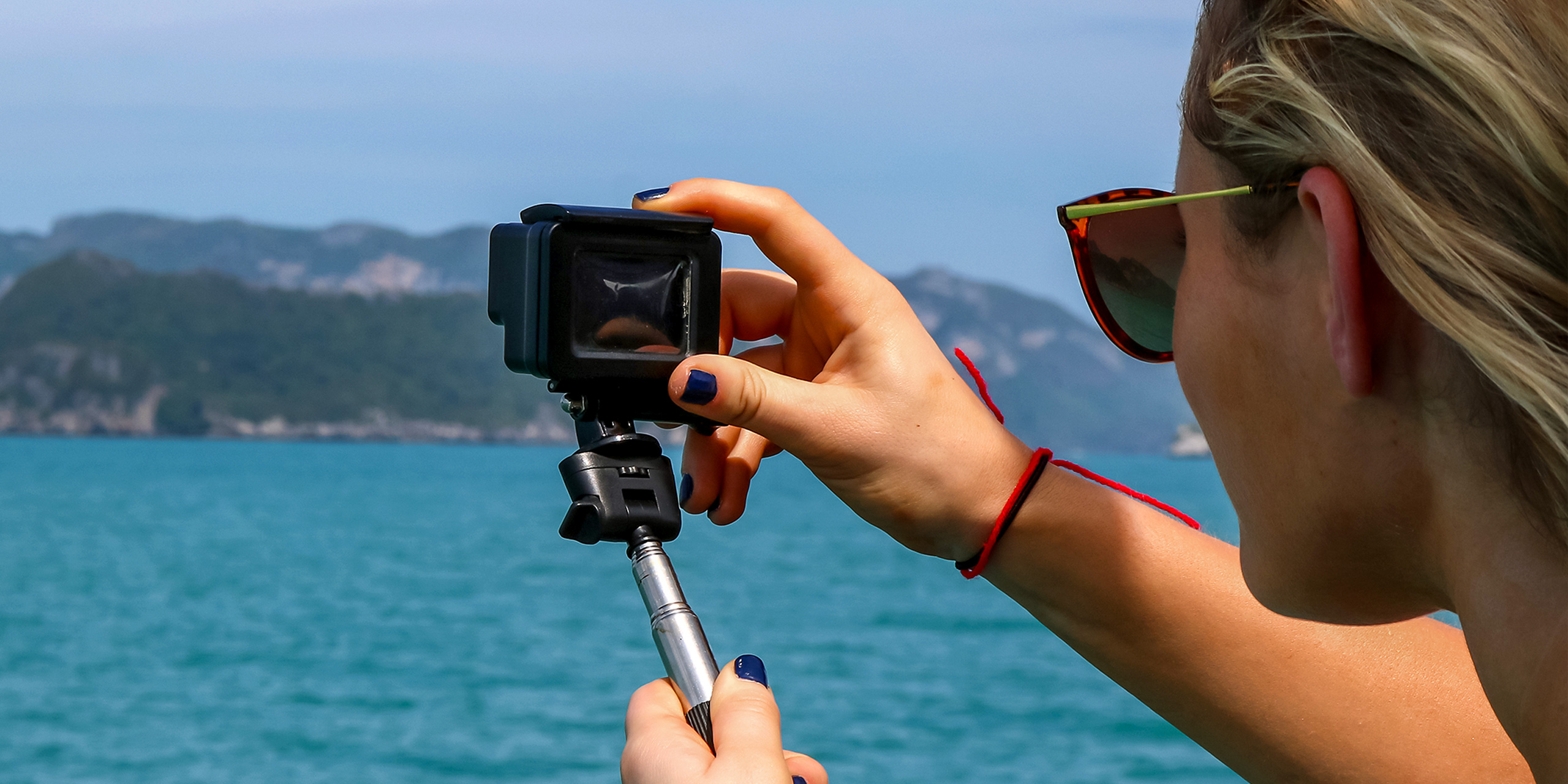 European girl tourists enjoy the GoPro camera and view of the island and the sea on the boat.
