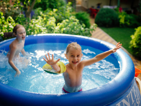 Two siblings splashing in kiddie pool