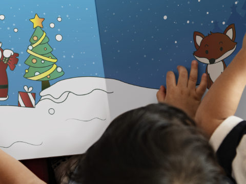 Over-the-shoulder view of three children reading a Christmas storybook